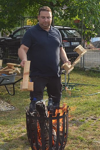 Ein Mann bestückt den Feuerkorb mit Holz