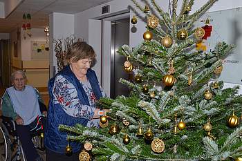 Eine Frau schmückt den Christbaum.