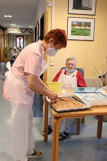 Eine Betreuerin verteilt Teig auf dem Blech.