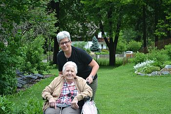 Eine Pflegerin mit einer alten Dame im Rollstuhl