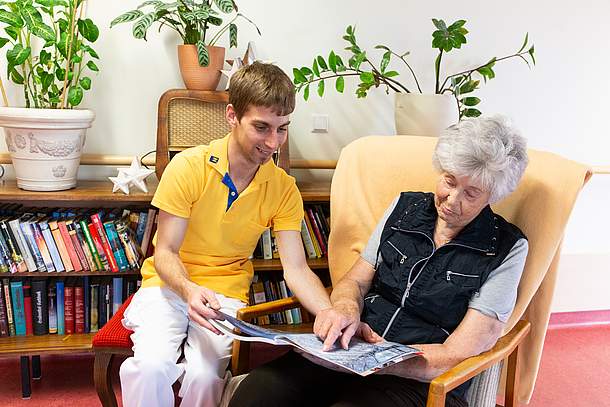 Pfleger zeigt Bewohnerin ein Fotobuch