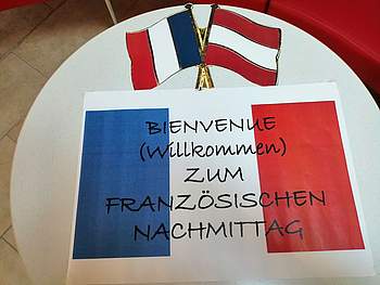 Ein Zettel mit der französischen Flagge, auf dem steht: "Willkommen zum französischen Nachmittag".